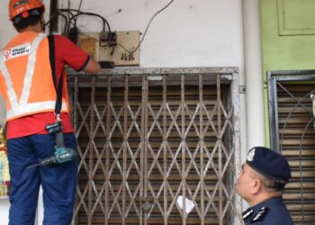 BAHRIN MOHD. NOH (kanan) melihat operasi pemotongan bekalan elektrik ke atas sebuah premis yang disyaki menyediakan perkhidmatan perjudian nombor ekor haram di Taman Muhibbah, Kluang.