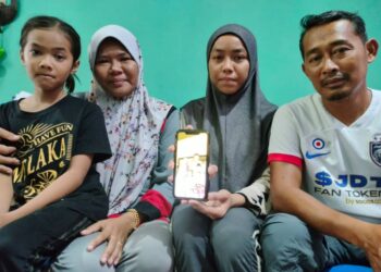 RIFA NUR HANA (dua dari kanan) bersama ayah dan ibunya menunjukkan gambarnya dengan arwah Shahrunizam ketika ditemui di Taman Sri Gading, Batu Pahat.