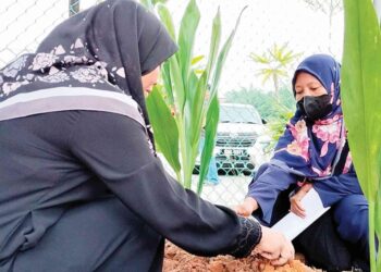 SITI Asmiza Azizan (kiri) di kubur anaknya yang selamat dikebumikan di Tanah Perkuburan Islam Matang Gerdu, Bagan Serai semalam. - UTUSAN/WAT KAMAL ABAS