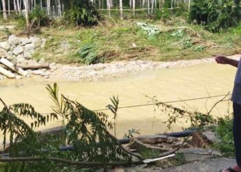 MOHD. Zukri Ariffin menunjukkan lokasi jambatan besi yang runtuh akibat banjir di Kampung Lubuk Tualang, Sik. – UTUSAN/NORLIA RAMLI