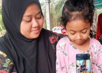 SITI Sarina Huri menunjukkan gambar arwah suaminya, Mohamad Afandy Mamosati sambil ditemani anaknya ketika ditemui di Sungai Mangkuk, Pasir Salak hari ini. - UTUSAN/AIN SAFRE BIDIN