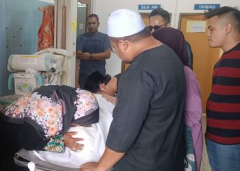 CHE Meriah Che Endut  mengucup jenazah anaknya, Ahmad Osama Ramadhan Laidin selepas selesai proses bedah siasat di Unit Forensik Hospital Dungun, hari ini. - UTUSAN/NIK NUR IZZATUL HAZWANI NIK ADNAN