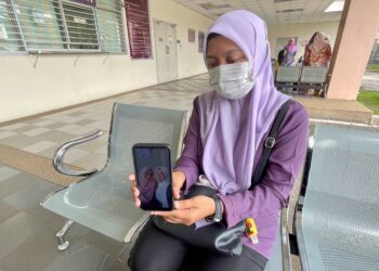 MELATI Abu Bakar menunjukkan gambar terakhirnya bersama Allahyarham Munirah ketika ditemui di pekarangan Jabatan Forensik HSB, Alor Setar. - UTUSAN/JAMLIAH ABDULLAH