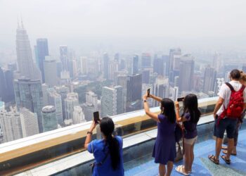 PELANCONG melihat pemandangan Kuala Lumpur dalam keadaan berjerebu ketika gambar dirakamkan dari Menara KL di sini, hari ini. -UTUSAN/SADDAM YUSOFF