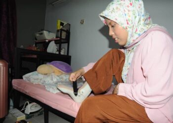 ARISHA Maisarah  Nasruddeen membetulkan alat bantuan sokongan kaki yang mengalami masalah saraf di bilik asramanya selepas mendaftar masuk sebagai pelajar baharu bagi sesi akademik 2023/2024 UTM Skudai Johor Bahru disini. -UTUSAN/RAJA JAAFAR ALI