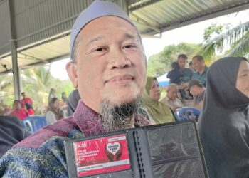 MOHD. Kamal Ismail, 55, menunjukan kad perlindungan insuran Agro Bank tajaan Yayasan Perbandaran Kluang yang diterimanya hari ini.