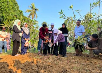 ANAK Allahyarhamah Munirah Abu Bakar menyiram air di pusara ibunya yang selamat dikebumikan di Tanah Perkuburan Islam Haji Talib di Kampung Paya Tengah, Padang Besar, Perlis hari ini. - UTUSAN/MOHD. HAFIZ ABD. MUTALIB