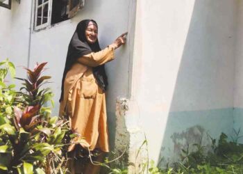 HASNAH Che Wil menunjukkan kesan retakan rumahnya yang dipercayai berpunca daripada premis besi buruk di Kampung Bunut Sarang Burung, Tumpat, Kelantan. – UTUSAN/ROSLIZA MOHAMED