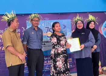 FAIZAH Jaarudin (dua dari kanan) menyampaikan sijil kelahiran kepada penjaga Orang Asli sempena program Menyemai Kasih Rakyat (Mekar) Siri Jelajah ke 75 buah perkampungan Orang Asli di Pos Brooke, Gua Musang, Kelantan hari ini. - UTUSAN/AIMUNI TUAN LAH