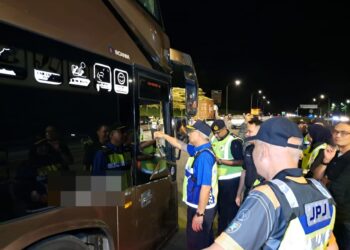 LOKMAN Jamaan (tengah) memeriksa dokumen seorang pemandu bas ekspres ketika mengetuai Op Patuh Khas Kenderaan Komersial di Plaza Tol Jitra, Kubang Pasu.
