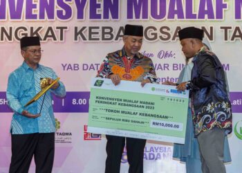 AHMAD Zahid Hamidi menyerahkan cek kepada Tokoh Mualaf Kebangsaan, Wan Masindra Juja dalam Majlis Konvokesyen Mualaf Madani Peringkat Kebangsaan 2023 di Bangi, semalam. – UTUSAN/FARIZ RUSADIO