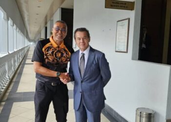 MOHD. Zaki Sadri (kiri) dan Mark William bersalaman selepas menyelesaikan kes saman fitnah mereka di Mahkamah Sesyen Kuala Lumpur hari ini.