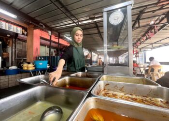 NOR  Juliana Aziz,26, memeriksa lauk pauk di Warung Kak Long dan Kak Ngah di Kangar, Perlis semalam.-UTUSAN/MOHD. HAFIZ ABD. MUTALIB