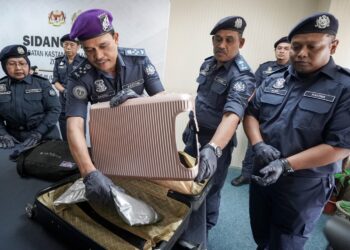 SAZALI Mohamad menunjukkan dadah yang disorok dalam bagasi yang diubahsuai di Kompleks Kastam Kargo, Sepang. - UTUSAN/FAISOL MUSTAFA