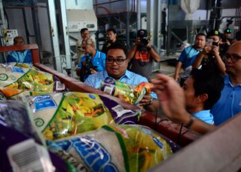 SETIAUSAHA Politik Menteri Besar, Mohd. Farid Mohd. Nor melihat beras putih tempatan yang disiap dibungkus oleh syarikat pembekal, Mumtaz Iman Sdn. Bhd. di Indera Mahkota di Kuantan, Pahang. - FOTO/SHAIKH AHMAD RAZIF