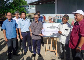 MOHAMAD Abdul Hamid (tiga dari kanan) ketika menyerahkan bangsal kepada nelayan di kawasan Selatan Pulau Pinang yang menerima skim SIMP di Bayan Lepas, semalam.