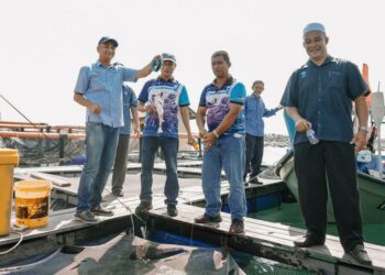 MUHAMMAD Faiz Fadzil (kiri) melawat sangkar ternakan ikan jenahak dan merah dalam sangkar yang diusahakan PNK Kuala Besut, Besut, hari ini.