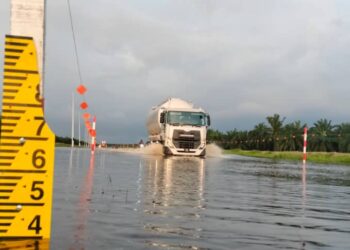 SEBUAH treler melalui Jalan Bagan Serai-Selama di Bagan Serai, Perak yang dinaiki air berikutan hujan lebat. - UTUSAN/WAT KAMAL ABAS
