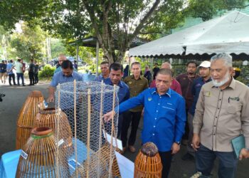 SAARANI Mohamad (tengah) melihat peralatan menangkap ikan yang dipamerkan pada program pelepasan benih ikan di perairan umum dan perasmian Jeti Nelayan Darat Kampung Luat di Lenggong hari ini. - UTUSAN