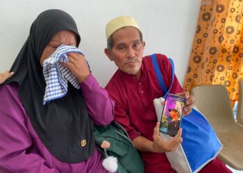 NUR Aisyah Muli bersama suami, Sazali Ali menunjukkan gambar arwah Muhammad Qusyairie di Pusat Forensik Hospital Port Dickson  hari ini.- UTUSAN/NOR SHAFAWATI YUP.