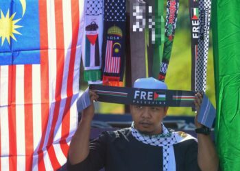 MOHD. Sam Mhmd Tahar menunjukkan bandana berkaitan sokongan terhadap rakyat Palestin yang dijualnya sempena program Palestin Kita Bersama anjuran Masjid Dato' Klana Petra Mubarak Al-Haj, Sungai Landak, Ampangan di Seremban, Negeri Sembilan. - UTUSAN/MOHD. SHAHJEHAN MAAMIN