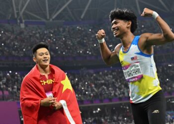 MUHAMMAD Azeem Fahmi (kanan) meraikan kemenangan tempat ketiga dalam acara 100 meter lelaki Sukan Asia Hangzhou di Zhejiang, China 
kelmarin. Memerhatikan Azeem pemenang pingat emas, Xie Zhenye. – AFP