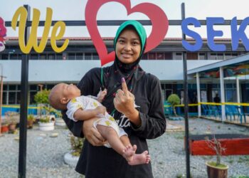 PENGUNDI muda, Nor Hafizah Hazmi, 26 membawa anaknya, Muhammad Muaiman Helmi yang berusia 44 hari menunjukkan jari yang ditanda dengan dakwat kekal selepas mengundi pada Pilihan Raya Kecil (PRK) Dewan Undangan Negeri (DUN) Pelangai di Pusat Mengundi Sekolah Kebangsaan (SK) Felda Kemasul.