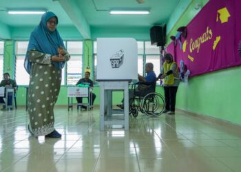 Petugas Suruhanjaya Pilihan Raya (SPR) membantu warga emas berkerusi roda untuk menunaikan tanggungjawab mengundi pada Pilihan Raya Kecil (PRK) Dewan Undangan Negeri (DUN) Pelangai di Pusat Mengundi Sekolah Kebangsaan (Felda) Kemasul, Pelangai di Bentong, Pahang. - FOTO/FARIZ RUSADIO