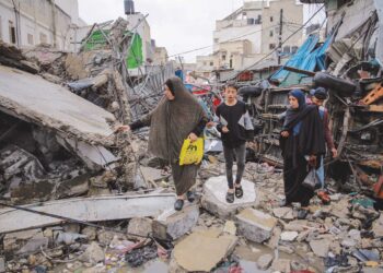 Rakyat Palestin melihat sisa bangunan berdekatan pasar Al-Zawiya di Gaza yang musnah akibat dibom tentera Zionis Israel. – AFP