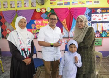 MOHD. Azmawi Fikri Abdul Ghani (tengah) menyampaikan sumbangan kepada Wan Normarlisa Sahila Wan Azmi di Sekolah Kebangsaan Gua Musang, Gua Musang, Kelantan semalam. - UTUSAN/AIMUNI TUAN LAH