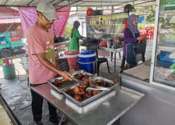 FAIZAL Ahmad Sadeli menggoreng ayam di kedai nasi ayam kukus di Kampung Bahagia di Teluk Intan. - UTUSAN/AIN SARFE BIDIN