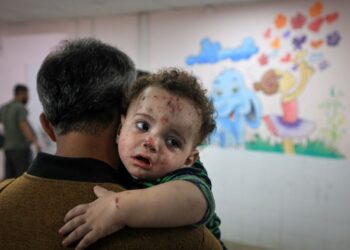 SEORANG penduduk mendukung anak kecil yang cedera akibat serangan Israel di Gaza. - AFP