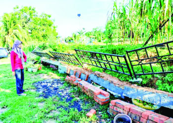 SHAHILA Manat menunjukkan runtuhan tembok penahan tanah yang berlaku di hadapan rumahnya di Jalan Semarak Api 3, Rumah Rakyat Gunung Lambak, Kluang.