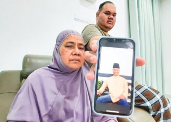 ZAITON Othman bersama anak bongsunya, Ahmad Firdaus Jasmi menunjukkan gambar Mohd. Hafiz ketika ditemui di rumahnya di Kulim. -UTUSAN/AZAHAR HASHIM