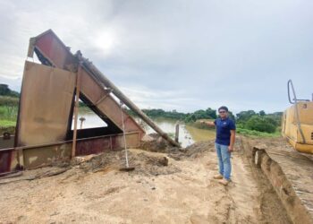 MUHAMMAD Ammirull Asraf Abdul Wahab mengambil langkah berjaga-jaga memindahkan peralatan memproses pasir miliknya agar kerugian dialami ketika banjir dua tahun lalu tidak berulang. - UTUSAN/NORHAFIZAN ZULKIFLI