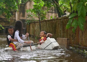 SEKUMPULAN kanak-kanak mengambil kesempatan bermain air dalam kejadian banjir di Kampung Gong Tok Nasek, Kuala Terengganu. - UTUSAN/PUQTRA HAIRRY ROSLI