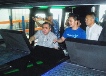 ANTHONY Loke Siew Fook diberi penerangan mengenai operasi bot prototaip Hydroglyder selepas pelancarannya di Batu Berendam, Melaka. - UTUSAN/AMRAN MULUP
