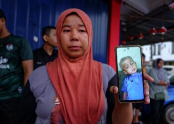 NOR AMIZA Che Kar menunjukkan gambar anaknya yang dipercayai hilang terjatuh dalam longkang di Jalan Bukit Baru, Bukit Palah, Melaka. - UTUSAN/SYAFEEQ AHMAD