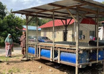 MOHD. Shaffien Mohmood (kiri) melihat rumah rakit yang telah dibaik pulih bagi menghadapi musim tengkujuh di Kampung Limau Kasturi, Gua Musang, Kelantan semalam-UTUSAN/AIMUNI TUAN LAH
