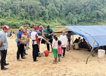 SYED Ibrahim Syed Ahmad (tengah) menyumbangkan barang makanan kepada penduduk Orang Asli etnik Bateq di tepi Sungai Tembeling berdekatan Kuala Tahan, Jerantut. – UTUSAN/HARIS FADILAH AHMAD