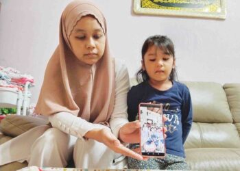 NATASHA AIDURA Mohd. Ezrin Shah Singh (kiri) bersama Nur Ariana Raisha Mohammad Hafiz menunjukkan gambar keluarga ketika ditemui di kediaman mereka di Taman Duyong Permai, Duyong, Melaka.