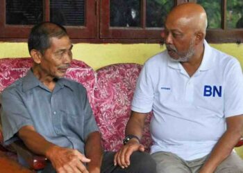 RAJA Mohamed Affandi (kanan) beramah mesra dengan seorang penduduk di Felda Kerteh 5, semalam.