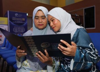 NORSIAH Ashaari (kiri) dan Nurin Awatif Mohd. Fizam melihat sijil ijazah doktor falsafah yang diraih arwah Mohd. Fizam Zainon sempena Istiadat Konvokesyen Universiti Malaysia Perlis (Unimap) Ke-18 di Dewan Ilmu, Unimap, Arau, Perlis semalam. – MINGGUAN/IZLIZAN OTHMAN