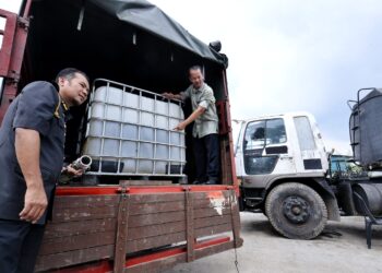 MUHAMMAD Zahir Mazlan (kanan) menunjukkan minyak diesel dalam tangki IBC yang dirampas hasil kejayaan serbuan Op Tiris di sebuah premis tidak bernombor di Jalan Industrial Gala 12, Seremban hari ini.-UTUSAN/MOHD. SHAHJEHAN MAAMIN.