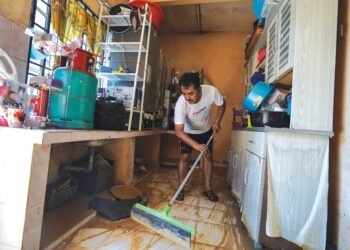 Mangsa banjir, Wan Mohd Zaharuddin Wan Rusli membersihkan rumahnya di Kampung Cemperai, Dengkil,Selangor selepas dilanda banjir kelmarin. - UTUSAN/FAISOL MUSTAFA