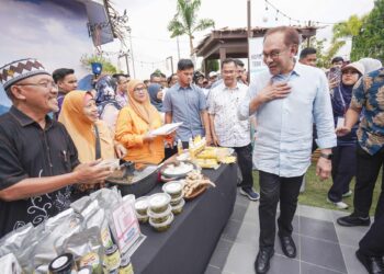 Anwar Ibrahim beramah mesra dengan usahawan ketika melawat gerai jualan selepas melancarkan Karnival Usahawan Desa (KUD) di Anjung Floria, Putrajaya, semalam. - UTUSAN/FAISOL MUSTAFA