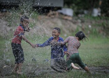 GELAGAT kanak-kanak yang tidak melepaskan peluang bermain air hujan di Bandar Seri Putra di sini, baru-baru ini.-UTUSAN/FAIZ ALIF ZUBIR