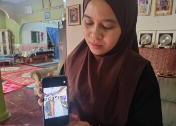 FATIN Hazirah Saleh menujukkan gambar ayah dan ibunya yang terbabit dalam kemalangan ketika mahu ke masjid dalam kejadian di Jalan Juasseh Terusan Seberang, Kuala Pilah, semalam. Bapanya, Saleh Ali, meninggal dunia ketika diberikan rawatan HTAN, Kuala Pilah.-UTUSAN/NOR AINNA HAMZAH.