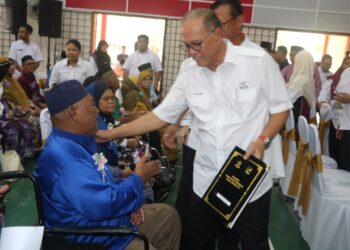 WAN Rosdy Wan Ismail menyampaikan surat hak milik tanah kepada Mohd Karim Shukran di Felda Jengka 25, Temerloh hari ini. - UTUSAN/SALEHUDIN MAT RASAD