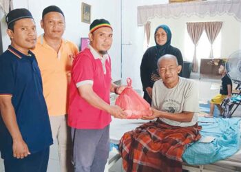 RAHIM Rohkim Iska (tengah, belakang) menyaksikan bantuan diserahkan kepada Turiman Masri @ Sairon dekat rumahnya di Kampung Sungai Serdang, Kapar, di Klang, Selangor.